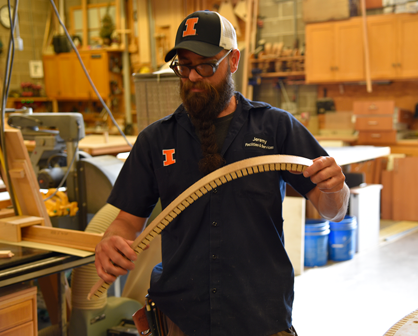 An F&S mill worker reviews a half-circular piece of wood that has just been fabricated.