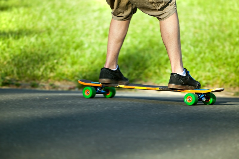 An individual using a longboard in the park