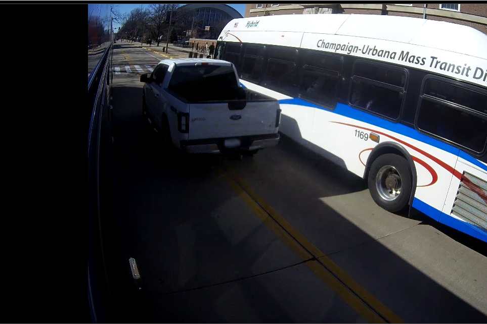 A truck passes a stopped bus illegally on Gregory Drive by passing a double yellow line