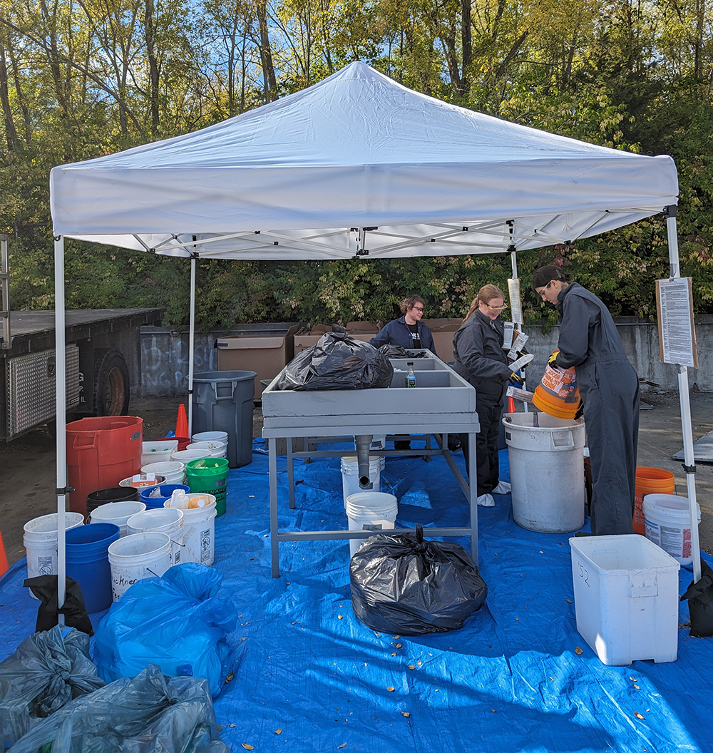 Materials being sorted under a tent for the Waste Characterization & Opportunity Assessment