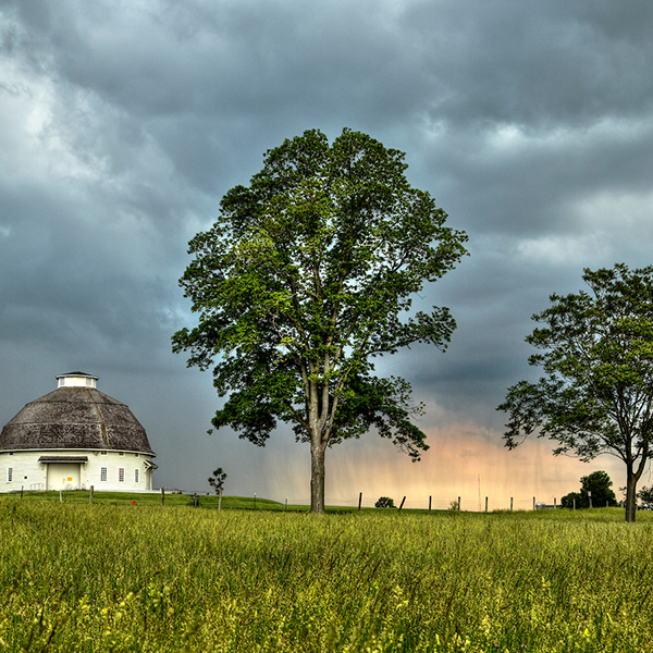Image of one of the round barns on South Farms being shown with a thunderstorm approaching