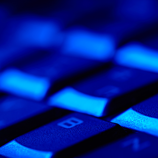 Close up of a computer keyboard key under a blue light
