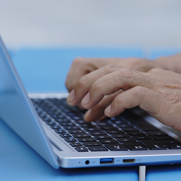 A close up of hands typing on a keyboard.
