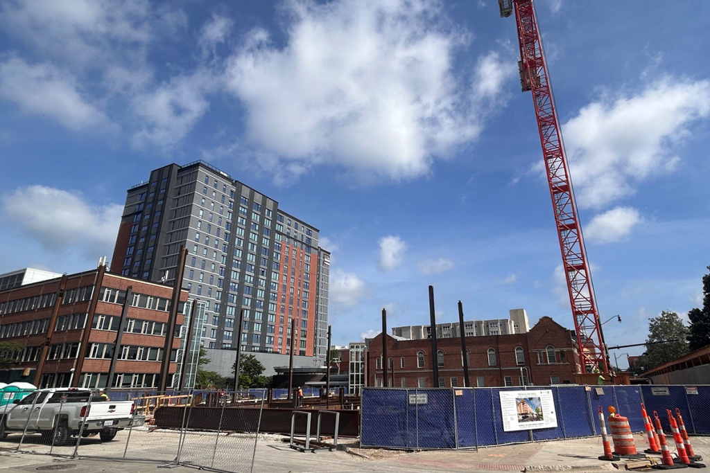 Structural steel beams are rising from the foundation on the construction site for the new facility on the location of the former Illini Hall. A crane is being used to support he beam work.