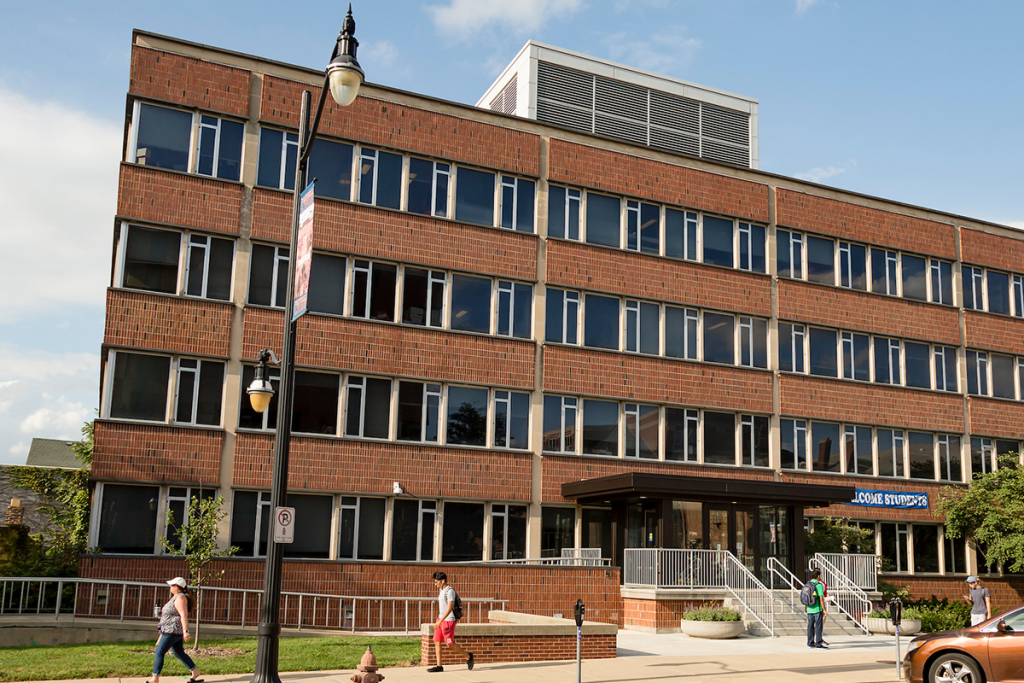 South facade of the Turner Student Services Building along John Street. Several individuals are walking on the sidewalk in the foreground.