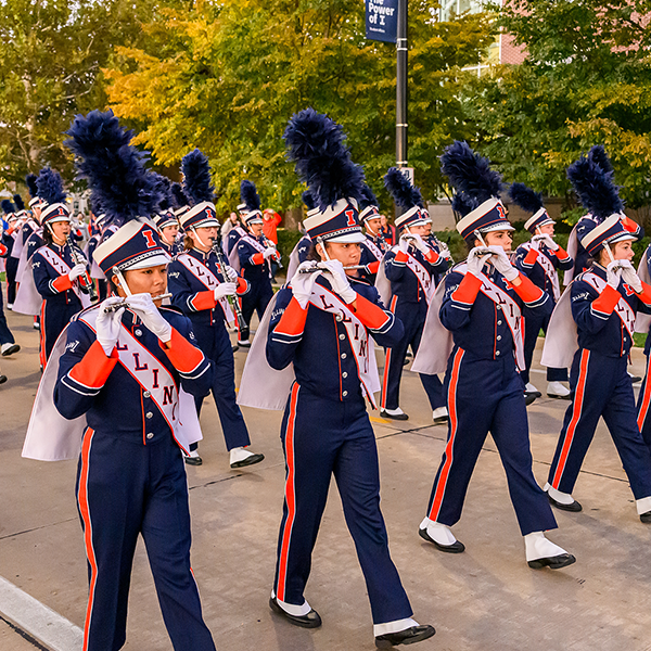 Marching Illini band members playing their instruments as they walk down the street