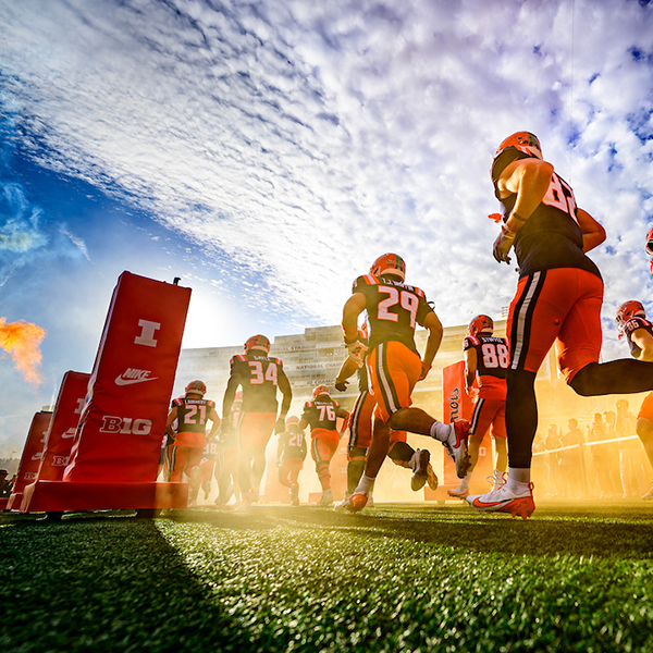 Illini football players run out on the field at Gies Memorial Stadium.