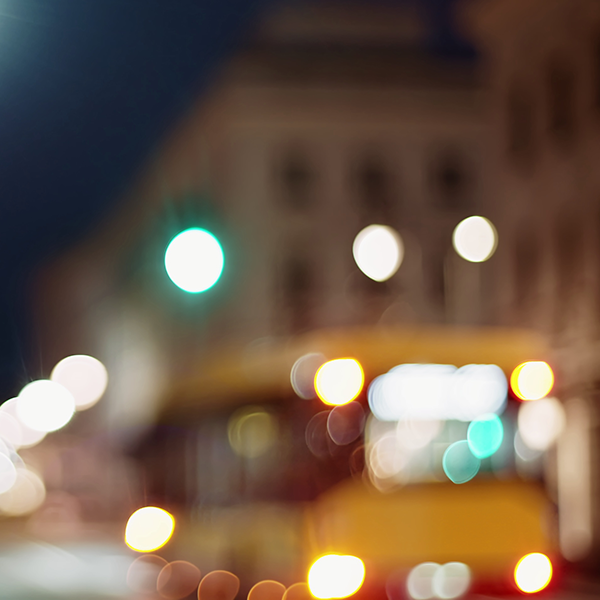 still image of bokeh city life cityscape blurred background urban street illuminated in evening yellow bus public transport and people pedestrians walking in slow motion downtown cityscape night illumination